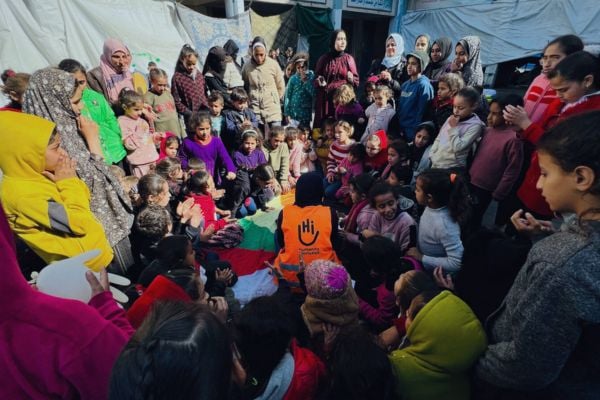 A crowd of young people surround an HI social worker, Gaza.