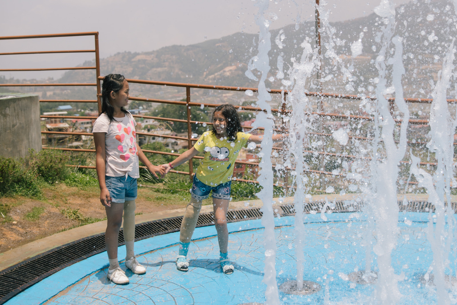 Nirmala and Khendo, two girls who lost a leg in the Nepal earthquake, stand on crutches.