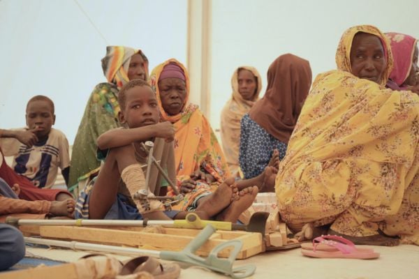 WOmen and children sit on the ground at an HI rehabilitation clinic, eastern Chad.