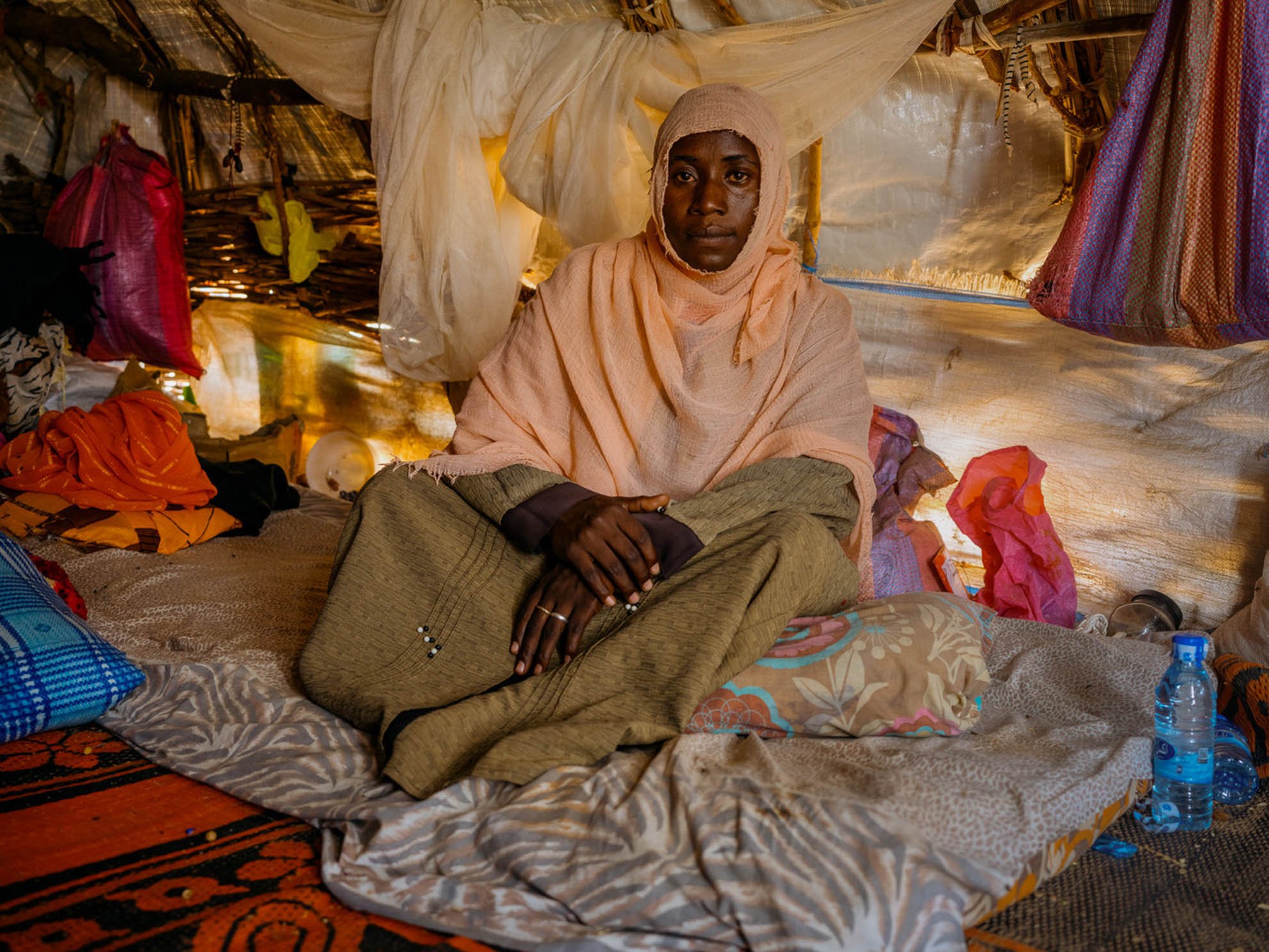 Nawali is sitting on a mattress inside her shelter 