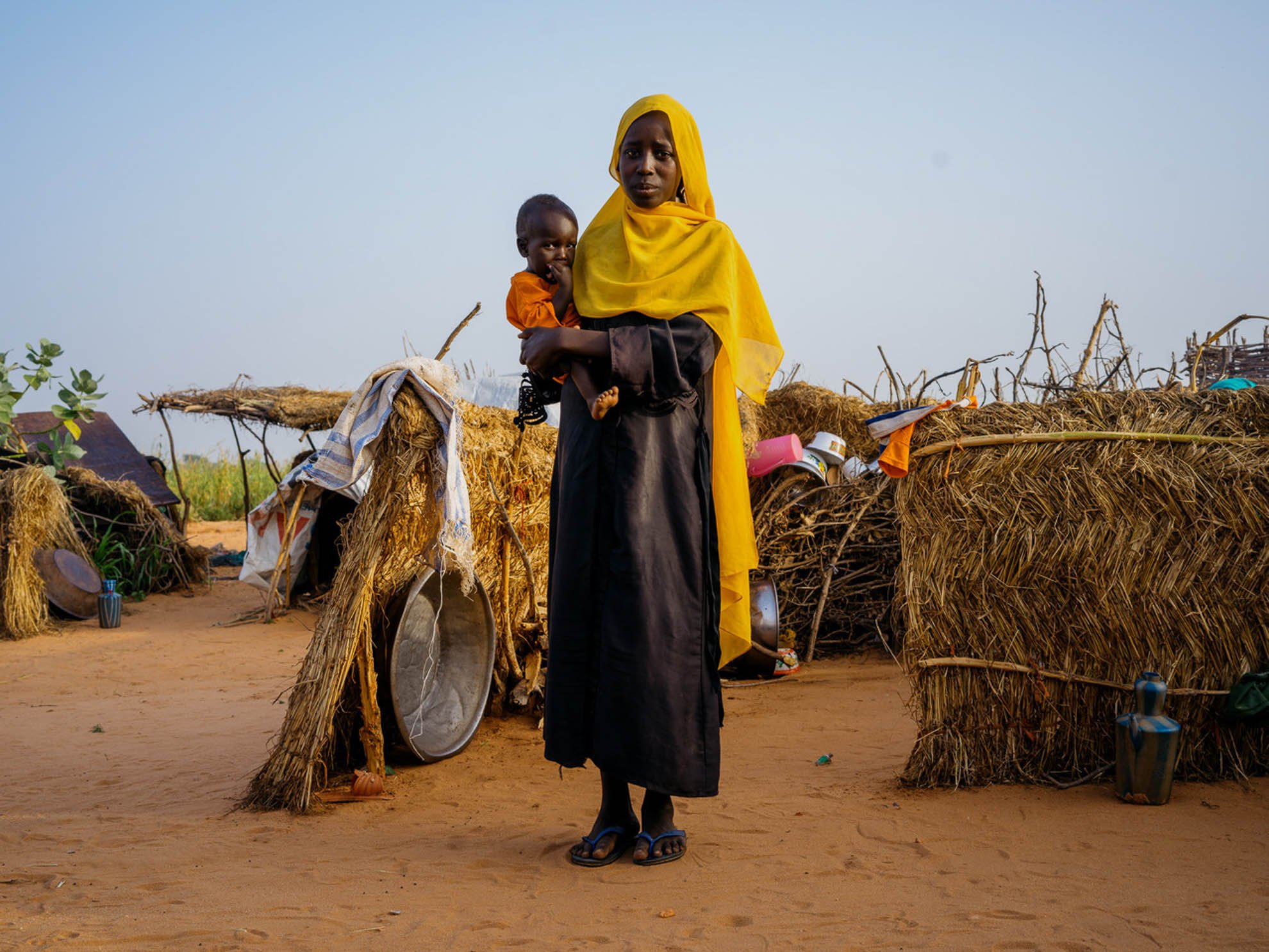 Zuhal holding her baby brother Said in the middle of a makeshift shelter