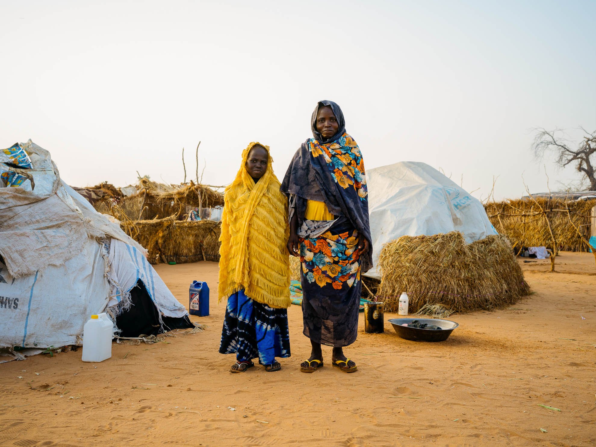 Fatna and her daughter Marwa standing in front of their shelter