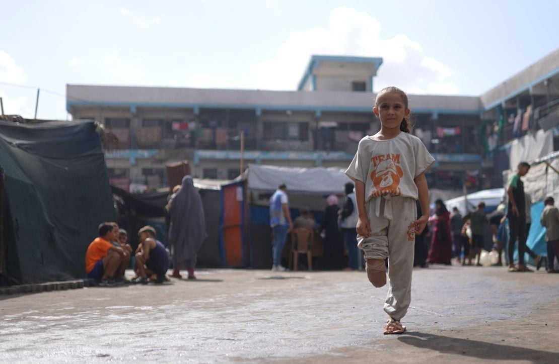 Gaza Crisis Appeal A young girl stands in a large courtyard in Gaza. Her trouser leg is rolled up and it is visible that the lower limb of her right leg has been amputated