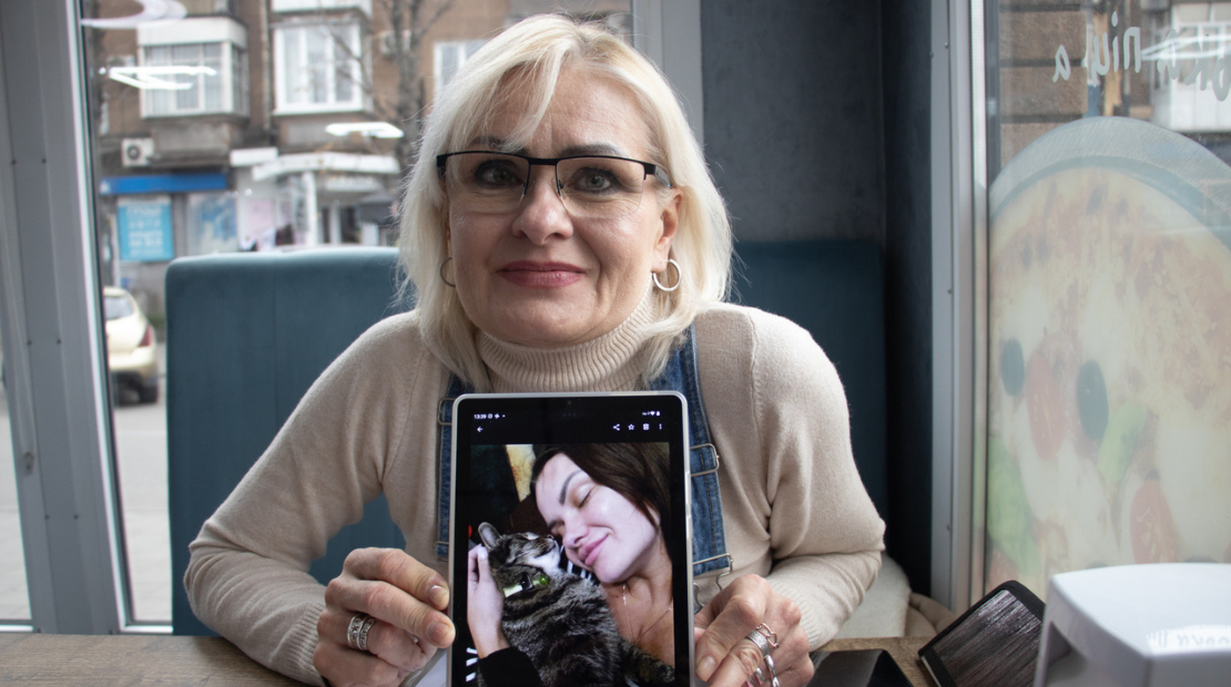 Elena, 53, and her daughter Yevgenia, 34, both survived bomb attack in eastern Ukraine. She is in a coffee shop showing a picture of her daughter and her cat. 